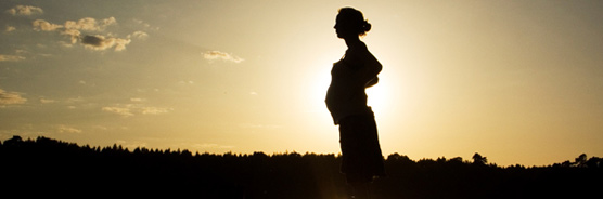 Schwangere Frau bei Sonnenuntergang